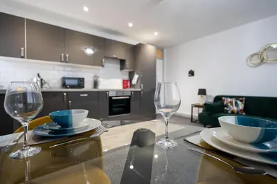 a table with two wine glasses and a kitchen at Suffolk Square in Sudbury