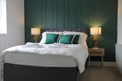 a bedroom with a large bed with green walls at Colchester town and castle modern flat with kitchen & private parking in Hythe