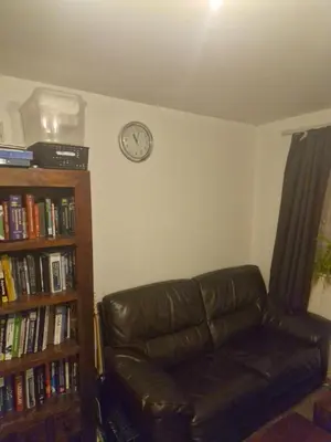a living room with a leather couch and a clock on the wall at Lovely One bedroom flat with free off road parking in Norton
