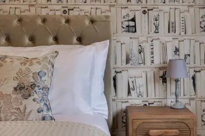 a bedroom with a bed and a wall of books at The Kings Arms Rooms in Saint Osyth