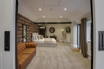a bedroom with a bed and a brick wall at The Kings Arms Rooms in Saint Osyth