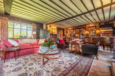 a living room with a red couch and a piano at Spectacular thousand year old Medieval manor house - Flemings Hall in Ipswich