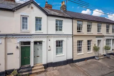an old white house with a green door at Victoria Cottage in Monks Eleigh