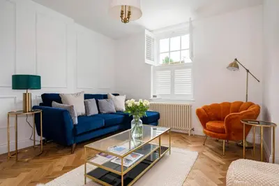 a living room with a blue couch and a chair at Victoria Cottage in Monks Eleigh