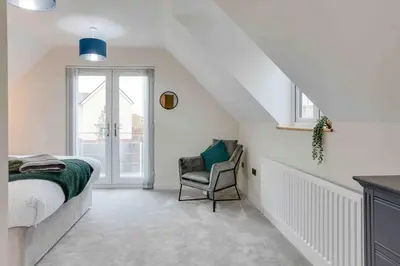 a bedroom with a bed and a chair in a attic at Kestrel Gardens Five Bedroom Homes in Great Dunmow