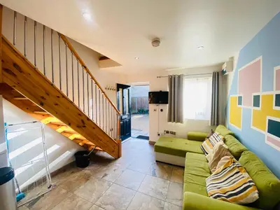 a living room with a green couch and a staircase at The Mews Flats - Cambridge, Central Location CB1 in Cambridge