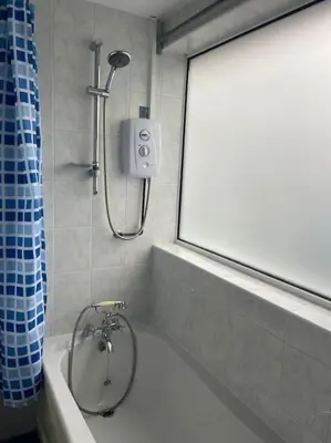 a bathroom with a shower and a tub and a window at One Bedroom Bungalow No1 - Secure Gated Parking in Basildon