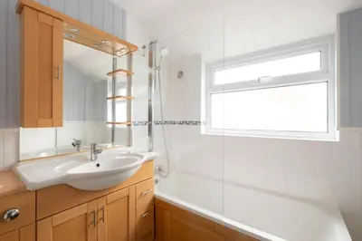 a bathroom with a sink and a tub and a window at 10 Jubilee Cottage in Leiston