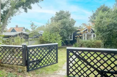 a gate in a yard with a house in the background at 3 Uplands, Thorpeness - Sleeps 3, Close to Beach, Boating Lake, Thorpeness Golf Club and Country Club - Aldeburgh Coastal Cottages in Thorpeness