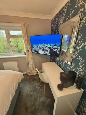 a bedroom with a desk and a bed and a tv at Three bedroom house in Harlow