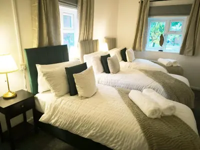 a bedroom with three beds with white sheets and pillows at Comfortable 2-Bed Home, Perfect for Work and Leisure in Colchester in Colchester