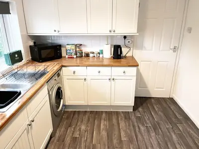 a kitchen with white cabinets and a washer and dryer at Comfortable 2-Bed Home, Perfect for Work and Leisure in Colchester in Colchester