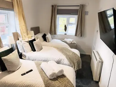 a room with three beds with towels on them at Comfortable 2-Bed Home, Perfect for Work and Leisure in Colchester in Colchester