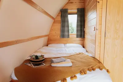 a small bedroom with a bed in a tiny house at Maglia Rosso by Wigwam Holidays in Bury Saint Edmunds