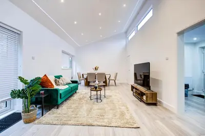 a living room with a green couch and a table at Sleek 3 Bedroom Home Sleeps 6 with Parking in Colchester