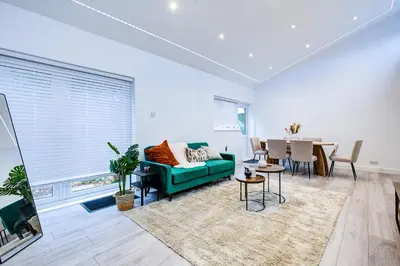 a living room with a green couch and a table at Sleek 3 Bedroom Home Sleeps 6 with Parking in Colchester