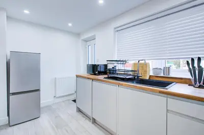 a kitchen with white cabinets and a sink and a window at Sleek 3 Bedroom Home Sleeps 6 with Parking in Colchester