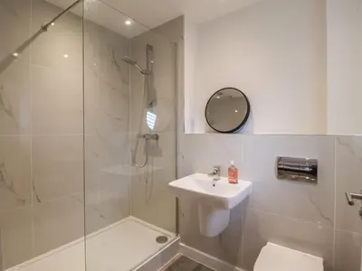 a white bathroom with a shower and a sink at Inishnee House in Ipswich