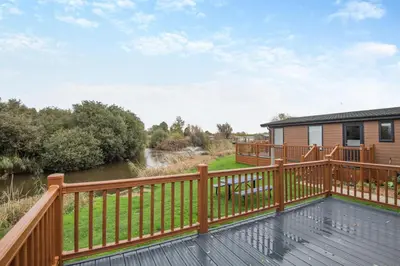 a deck with a wooden railing next to a river at 2 Bed in Welney oc-c30124 in Welney