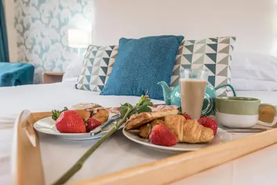 a tray with two plates of food and strawberries on a bed at Telford, Aldeburgh in Aldeburgh