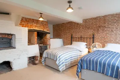 two beds in a room with a brick wall at River House in Kersey