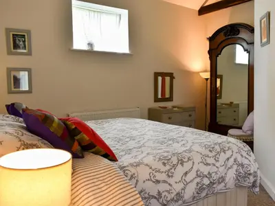 a bedroom with a large bed and a mirror at Evie Rose Cottage in Elsenham