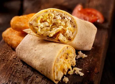 a burrito cut in half on a wooden cutting board at Artsy Minimalist Suite in Southend-on-Sea