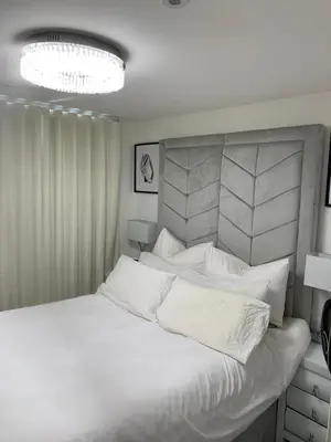 a white bedroom with a large bed with white pillows at BYK Homes, Hotels and Suites in Grays Thurrock