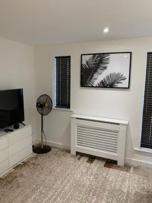 a living room with a flat screen tv and a fan at BYK Homes, Hotels and Suites in Grays Thurrock