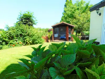 a garden with a gazebo in the background at Greenbank Cottage in Hilgay