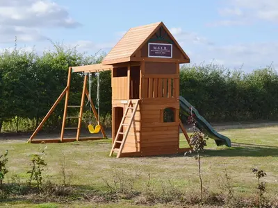 a small wooden playground with a slide and a swing at Railway Carriage One - E5337 in Wetheringsett
