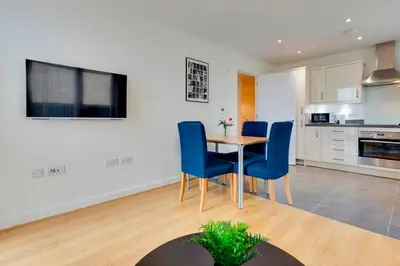a kitchen and dining room with a table and blue chairs at 54 Woodpecker Way · Modern apartment near Addenbrookes Free parking Pass the Keys in Cambridge
