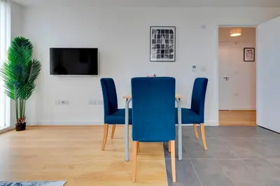 a dining room with a table and blue chairs at 54 Woodpecker Way · Modern apartment near Addenbrookes Free parking Pass the Keys in Cambridge