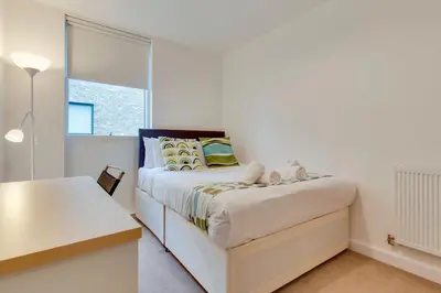 a white bedroom with a bed and a desk at 54 Woodpecker Way · Modern apartment near Addenbrookes Free parking Pass the Keys in Cambridge