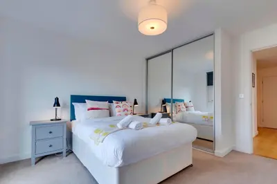 a bedroom with a large white bed and a mirror at 54 Woodpecker Way · Modern apartment near Addenbrookes Free parking Pass the Keys in Cambridge