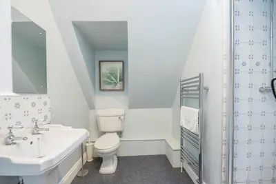 a white bathroom with a sink and a toilet at Buoys Cottage, Orford in Orford