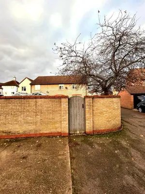 a brick fence with a gate and a tree at 2 Bedroom House off A12 Colchester in Lexden