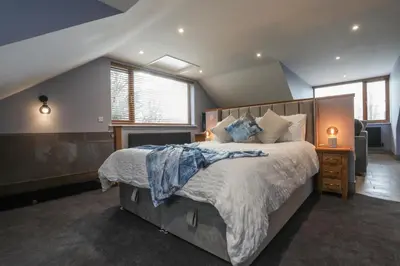 a bedroom with a large bed and some windows at Oak View Lodge Luxury Master Studio near Ipswich & Woodbridge in Playford