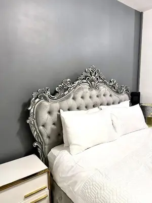 a bedroom with a white bed with a ornate headboard at Deluxe Spacious King Size Room in Hornchurch