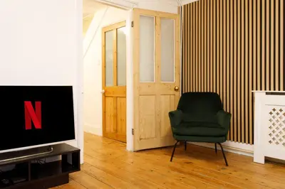 a living room with a television and a green chair at Cosy House - Stanstead Airport in Bishops Stortford