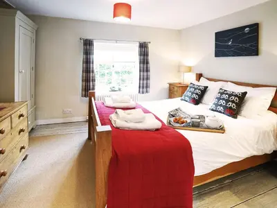 a bedroom with a bed with a red blanket at 6 Town Steps by The Suffolk Cottage Collection in Aldeburgh