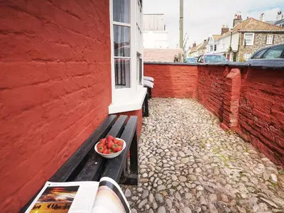 a bowl of fruit sitting on a bench next to a building at Tiger Villa by The Suffolk Cottage Collection in Aldeburgh