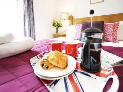 a breakfast tray with food on a bed at Tiger Villa by The Suffolk Cottage Collection in Aldeburgh