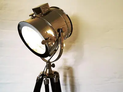 a lamp on a tripod against a wall at Hidden Cottage by The Suffolk Cottage Collection in Aldeburgh