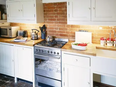 a kitchen with white cabinets and a stove at Hidden Cottage by The Suffolk Cottage Collection in Aldeburgh