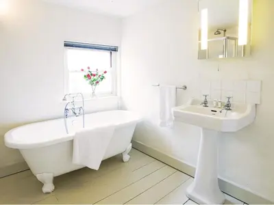 a white bathroom with a tub and a sink at Hidden Cottage by The Suffolk Cottage Collection in Aldeburgh