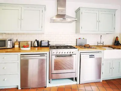 a kitchen with white cabinets and a stove top oven at Sandpiper Cottage by The Suffolk Cottage Collection in Aldeburgh