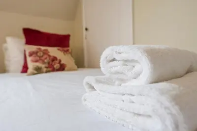 a pile of white towels sitting on a bed at Castle Cottage, Orford in Orford