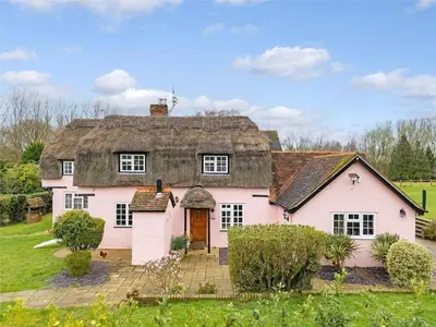 a large pink house with a thatched roof at Blackbrook Farmhouse with free off-street parking for 10 cars in Colchester