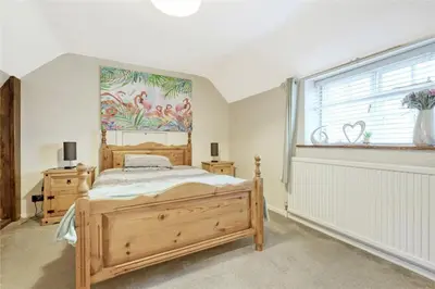 a bedroom with a wooden bed and a window at Blackbrook Farmhouse with free off-street parking for 10 cars in Colchester
